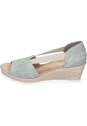 Miętowo-zielone buty na koturnie z otwartym palcem i elastycznymi paskami, z teksturowaną, plecioną podeszwą oraz miękkim, zamszowym materiałem cholewki.