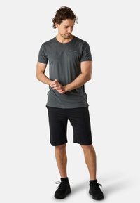 Mörkgrå kortärmad träningsskjorta med en strukturerad övre del, kombinerad med svarta shorts. Lätt material, åtsittande design.