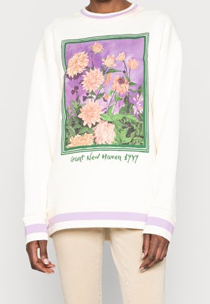 Sudadera color crema con un gráfico floral en rosa y verde sobre un fondo púrpura, con puños y dobladillo a rayas púrpuras.