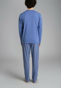 Top blu lungo a maniche, realizzato in tessuto morbido con colletto rotondo, abbinato a pantaloni a righe blu chiaro, caratterizzati da una vestibilità comoda.