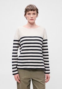 Μπλ�ούζα μακρυμάνικη με ρίγες, που διαθέτει μαύρες και κρεμ ρίγες σε οριζόντια διάταξη, βαθιά λαιμόκοψη, χαλαρή εφαρμογή και ελαφρύ ύφασμα με απαλό άγγιγμα.