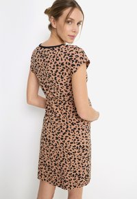 Φόρεμα με λεοπάρ σχέδιο σε μπεζ και μαύρο, με κοντά μανίκια και άνετη εφαρμογή. Ομαλό ύφασμα με στρογγυλή λαιμόκοψη και μήκος μέχρι το γόνατο.