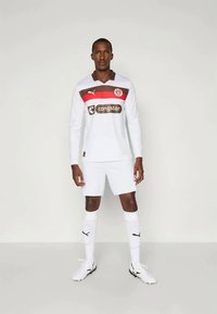 Λευκή ποδοσφαιρική φανέλα με μακριά μανίκια, με μαρόν και κόκκινο οριζόντιο σχέδιο, με το λογότυπο "congstar", συνδυασμένη με λευκά σορτς και κάλτσες.