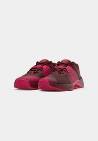 Pair of maroon and bright pink athletic shoes with textured soles and lace-up fronts on a plain white background.