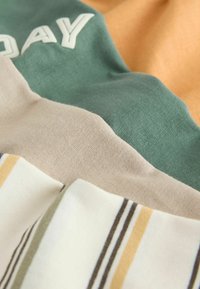 Mehrfarbiger Stoff mit grünen, beigefarbenen und orangen Abschnitten, zeichnet sich durch eine weiche Textur und horizontale Streifen mit gelben und grünen Akzenten aus.