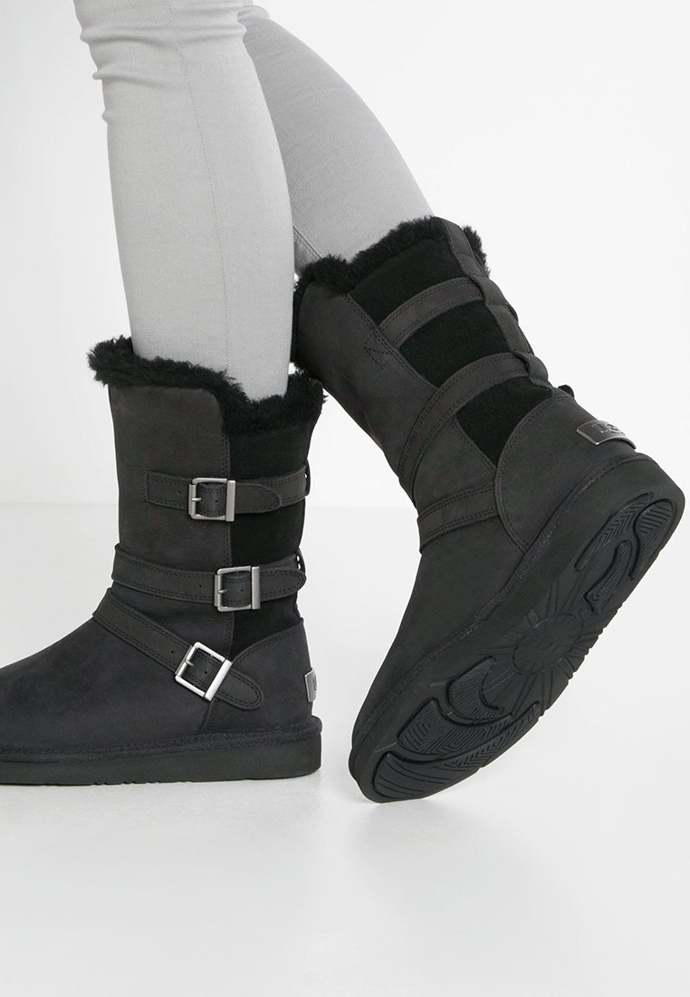 Bottes cheville en daim noir et textile avec détails à boucles, hauts doublés de fourrure et semelles en caoutchouc texturé. Dotées d'un talon plat et d'un bout arrondi.