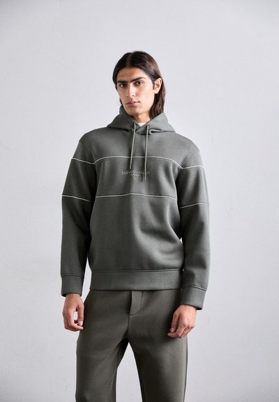 Bluza z kapturem w oliwkowej zieleni z białymi przeszyciami i kieszenią kangurką; w komplecie z pasującymi spodniami, oba wykonane z miękkiego materiału.