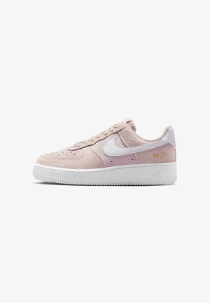 Sneakers basses Nike Air Force 1 en daim rose clair avec le swoosh Nike blanc et la semelle blanche, vues de côté.