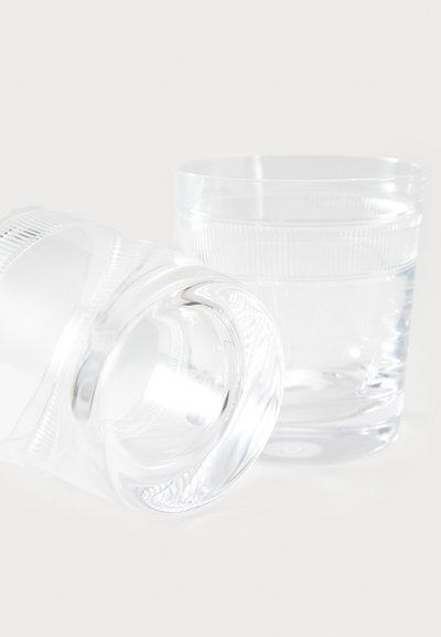 Vasos de cristal transparente con forma cilíndrica; uno está en posición vertical y el otro inclinado. Ambos presentan sutiles bandas con textura alrededor del borde superior.