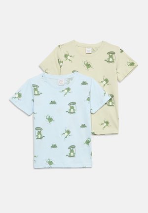 Kahes kehvade varrukatega laste t-särki, üks helesinine ja teine beež, mõlemal mängulised rohelised konna mustrid erinevates poosides.