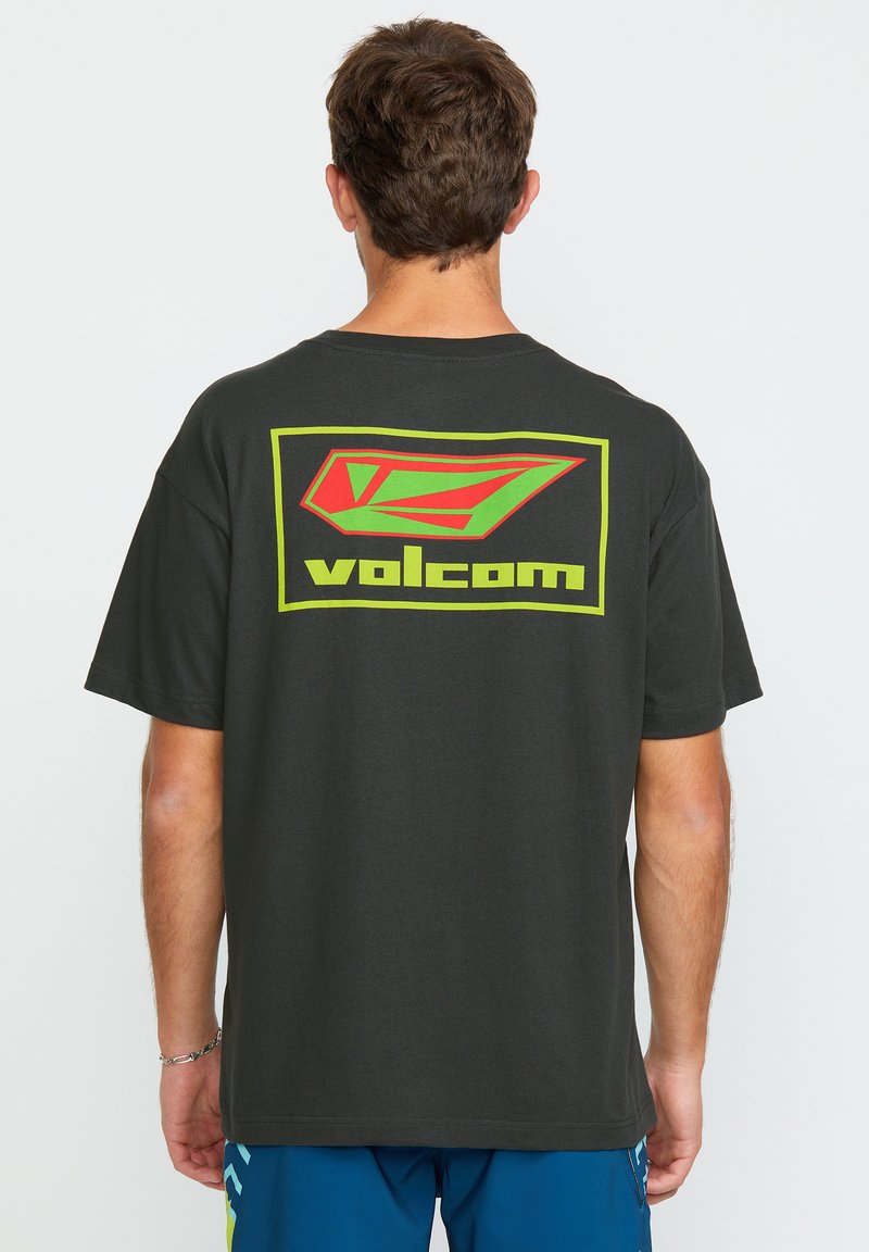 T-shirt noir à manches courtes avec un grand logo Volcom rouge et vert au dos, fabriqué en coton avec une coupe décontractée.