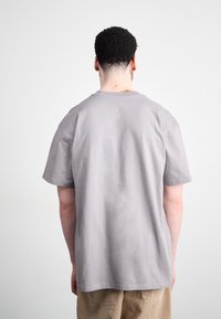 Gray cotton t-shirt with short sleeves and a relaxed fit, featuring a crew neck and a smooth texture. The back is plain without embellishments.