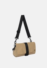 Béžová crossbody taška s černým popruhem, obdélníkový tvar, hladký povrch a kontrastní černé kování. Na jedné straně je logo.