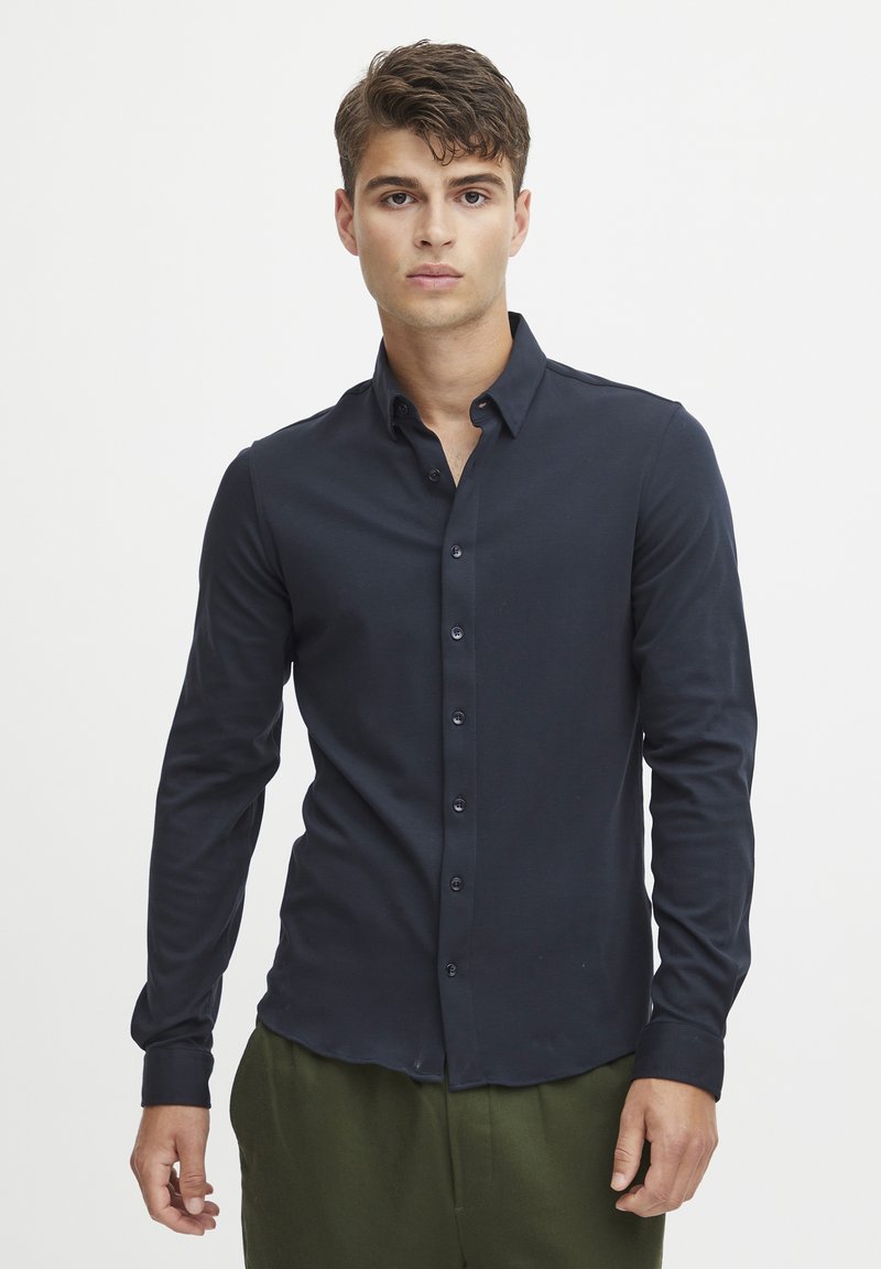 Marineblauwe overhemd met lange mouwen en een slim fit. Kenmerkend zijn de klassieke kraag en bijpassende knopen, gemaakt van zachte, gladde stof.