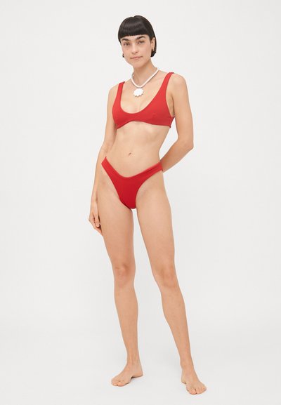 Červený bikini set s trojuholníkovým vrškom a vysokým pásom. Hladký materiál, minimalistický dizajn a tenké ramienka.