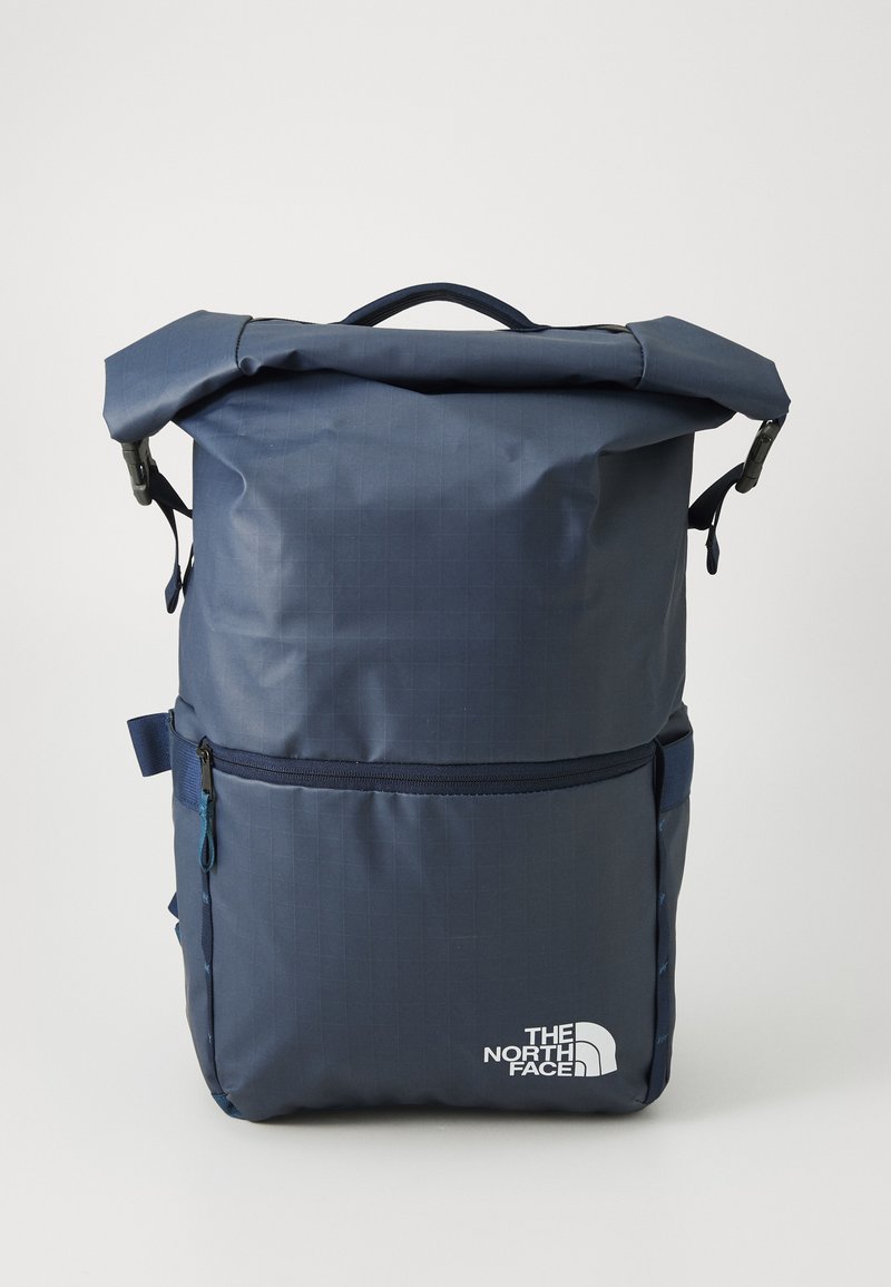 Navyblaue Rolltop-Rucksack aus strapazierfähigem Material, mit einer vorderen Reißverschlusstasche und dem weißen The North Face-Logo auf der Vorderseite.