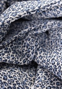 Geweven stof met een witte basis en een blauw luipaardprintpatroon, met een zachte textuur en soepel vallende draping.