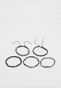 Set di cinque braccialetti con perline nere e grigie, alcune con accenti metallici, con legature regolabili, forme e texture delle perline variabili.