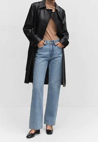 Černý kožený trenčkot, béžový top, světle modré džíny s vysokým pasem a černé boty na blokovém podpatku. Silueta s širokými nohavicemi a hladká textura.