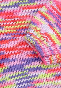 Sweter dziany z pionowymi paskami w kolorze różowym, czerwonym, fioletowym i zielonym. Tekstura jest miękka, wykonana z grubej włóczki w przytulnym designie.