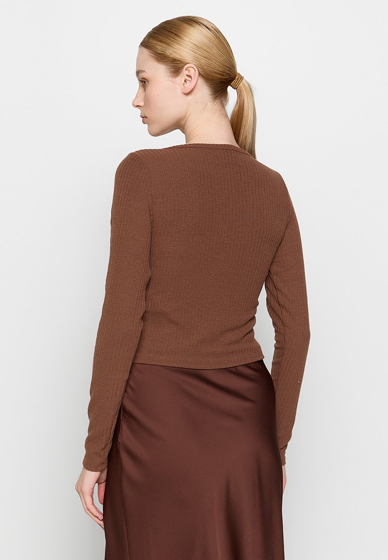 Braun gerippter Langarm-Oberteil, figurbetontes Design, Rundhals, strukturierter Stoff, kombiniert mit einem glatten braunen Satinskirt, Rückansicht.