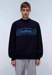 Sweatshirt azul-marinho feito de tecido macio, com uma faixa gráfica texturizada azul com o logótipo "NAPAPIJRI" ao longo do peito. Corte solto, punhos canelados.