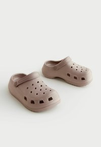 Ljusrosa plastklackar med ventilationshål och bakrem. Texturerade sidor med en slät yta, rundad form och vadderade sulor.