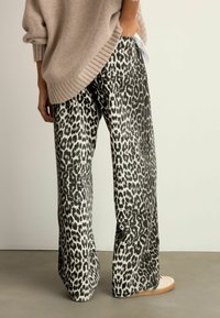 Pantaloni largi cu imprimeu leopard, dintr-un material texturat; model alb-negru, cu o croială confortabilă și talie cu șnur.