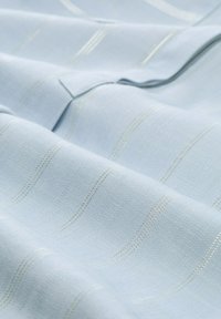 Helles blauer Stoff mit einer strukturierten Oberfläche und subtilen gewellten Streifen aus metallischem Faden, der eine glatte Oberfläche und ein elegantes Design zeigt.