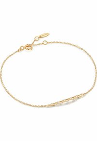 Goldfarbener Kettenarmreifen mit einem gebogenen Stäbchen, das fünf kleine, glitzernde Steine enthält. Karabinerverschluss mit angehängtem Markenetikett.