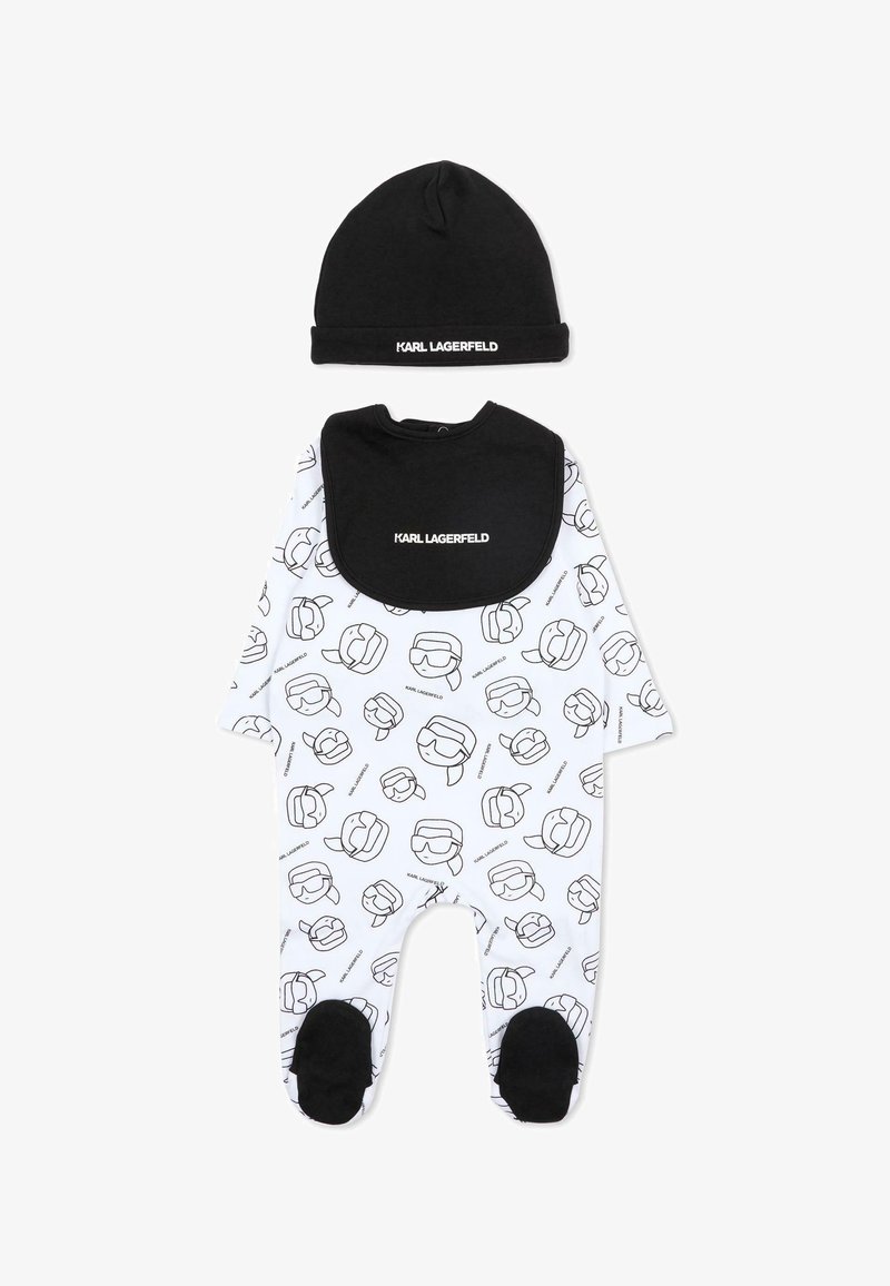 Czarno-biały zestaw niemowlęcy Karl Lagerfeld z czapką, śliniakiem i kombinezonem z zakrytymi stopami, zdobiony powtarzającym się wzorem kreskówkowej twarzy i nazwą marki.