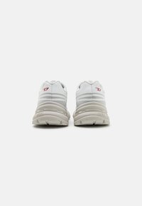 Weiße Sneaker mit einem oberen Teil aus glattem Leder, grauen Akzenten und strukturierter Sohle. Verfügt über ein abgerundetes Design und minimale Markierung an der Ferse.