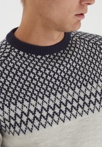 Sweter dzianinowy z geometrycznym wzorem w granatowym i jasnoszarym kolorze, z okrągłym dekoltem i teksturowanym materiałem.