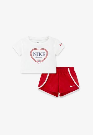 Nike children's outfit featuring a white short-sleeve top with blue and red logo, paired with red shorts with white trim and logo.