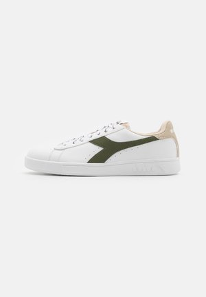 Sneaker bianco realizzato in pelle e camoscio, con logo verde oliva, dettagli beige e suola piatta in gomma. Include lacci e dettagli perforati.