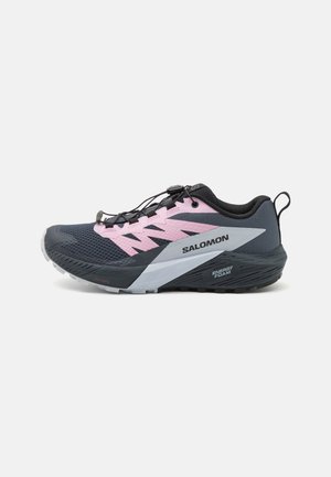 Zapatilla de running Salomon en navy y rosa, con parte superior de malla, cierre de cordones y acentos de logo. Suela texturizada con tecnología ENERGY FOAM.