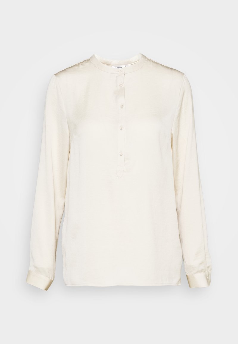Blusa a maniche lunghe di colore crema in tessuto liscio. Presenta un collo rotondo, una placca frontale con bottoni e polsini con bottoni. Design semplice.