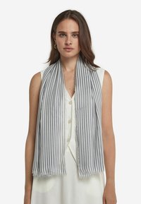 Let sval scarf i blå og hvide striber, med fransede kanter og en blød tekstur, draperet omkring skuldrene over en ærmeløs top.
