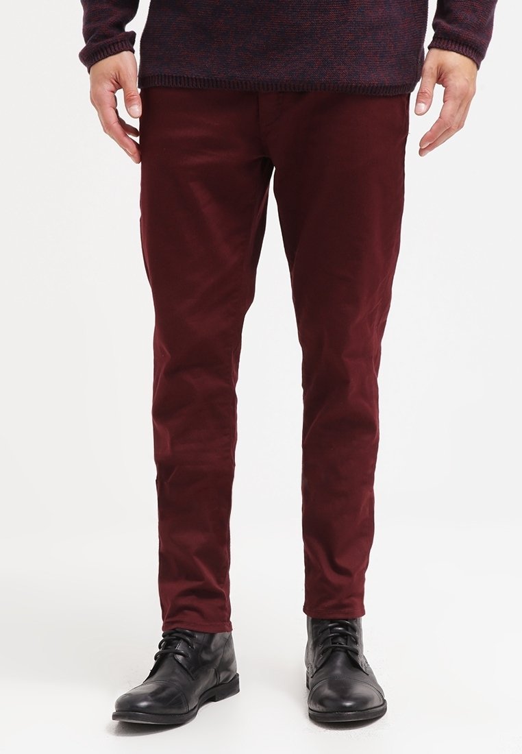 Pantaloni color bordeaux in cotone con design a taglio slim. Presentano tasche laterali e una texture liscia, abbinati a stivali neri con lacci.