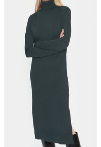 Pusero-mekko tummanvihreästä, ribbitetystä kankaasta. Pitkät hihat, suora siluetti, sivuhalkio helmassa, laskeutuu polven alapuolelle.