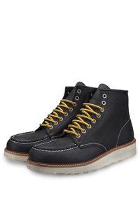 Stivali in pelle nera con lacci gialli, cuciture bianche e suola in gomma beige. Presentano un design alto alla caviglia e occhielli in metallo per l'allacciatura.