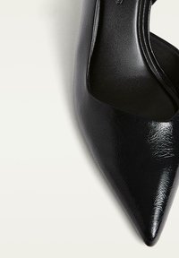 Escarpin noir à bout pointu avec une tige synthétique texturée, une doublure intérieure lisse et une silhouette élancée. Présente une coupe inclinée basse sur les côtés.