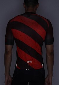 Jersey de ciclismo de manga corta en rojo oscuro con rayas diagonales negras, con textura perforada y acentos reflectantes en la base.
