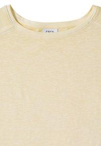 T-shirt jaune clair à col rond en tissu subtilement texturé avec un détail de couture froncée sur les coutures des épaules.