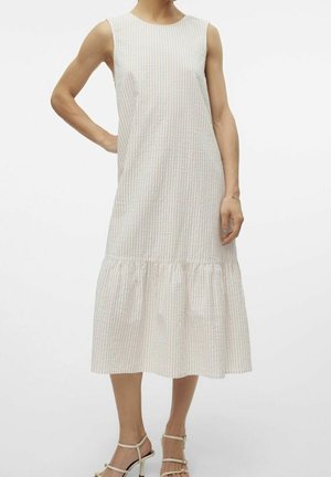 Mouwloze midi-jurk met lichtbeige en witte verticale strepen, met een geplooide zoom, gecombineerd met beige sandalen met bandjes en hoge hakken.