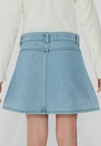 Jupe en denim de couleur bleu clair, forme évasée, avec des ourlets cousus et cinq passants de ceinture. La vue arrière montre une texture lisse et un minimum de détails.