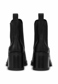 Black leather ankle boots with a chunky heel, featuring a smooth surface, side stitching, and fabric accents at the top.