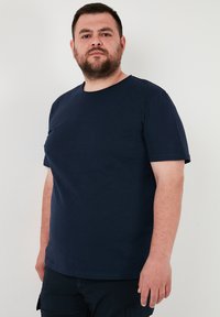 Tricou bleu cu mâneci scurte, confecționat din bumbac. Design cu guler rotund, având o textură fină, cu un aspect simplu și discret.