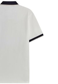 Polo a maniche corte in cotone bianco con colletto e polsini blu navy. Texture liscia, vestibilità classica e design semplice.