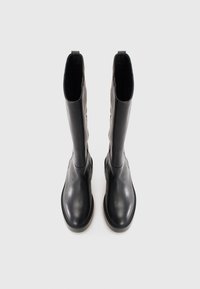 Černé kožené vysoké boty nad kolena s hladkým povrchem, kulatou špičkou a plochou podrážkou. Mají minimalistický design bez viditelného kovového příslušenství nebo ozdob.